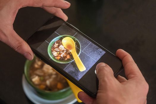 Hands of male blogger photographing mushroom soup through smart phone at a cafe