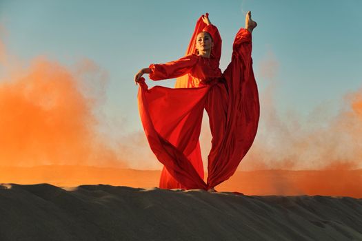 Woman in red dress dancing in the desert at blue sky