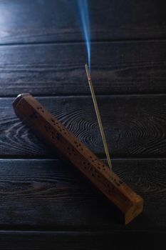 Focus on incense stick and smoke in a wooden stand. Symbol Japanese culture