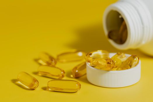 Omega-3 fish oil capsules in the bottle on yellow background for healthcare concept