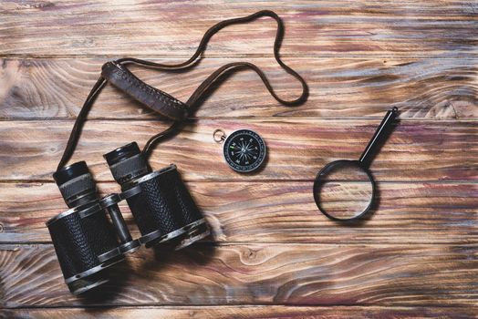 wooden background with binocular compass magnifying glass