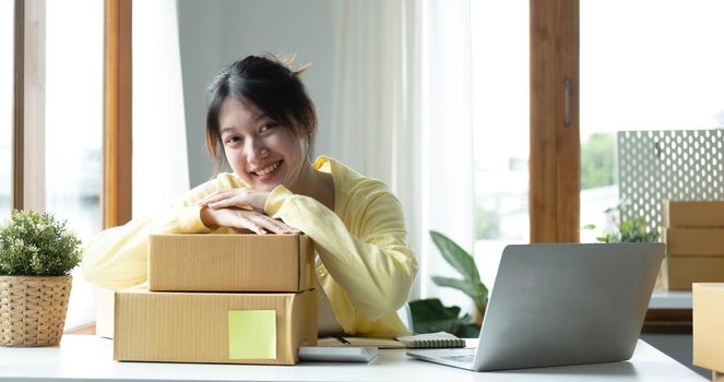 Starting small businesses SME owners female entrepreneurs Use a laptop or notebook to receive and review orders online to prepare to pack boxes, sell to customers, SME online business ideas..