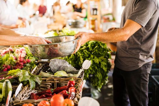 seller hand holding stainless steel container while customer buying vegetable market