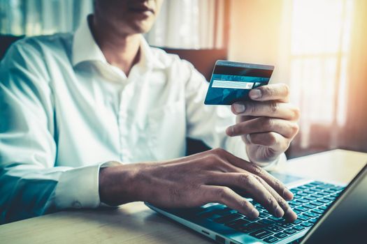 Young man use credit card for shopping payment online on laptop computer application or website. E-commerce and online shopping concept.