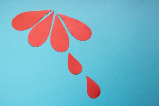 The concept of the World Blood Donor and Hemophilia Day. Red paper drops of blood on a blue background.