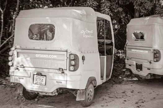 Tulum Mexico 02. February 2022 Old black and white picture of driving thru typical colorful street road and cityscape with tuk tuk cars traffic palm trees bars and restaurants of Tulum in Mexico.