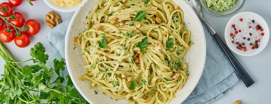 Banner with pesto pasta, bavette with walnuts, parsley, garlic, nuts, olive oil.Top view, long side, blue background