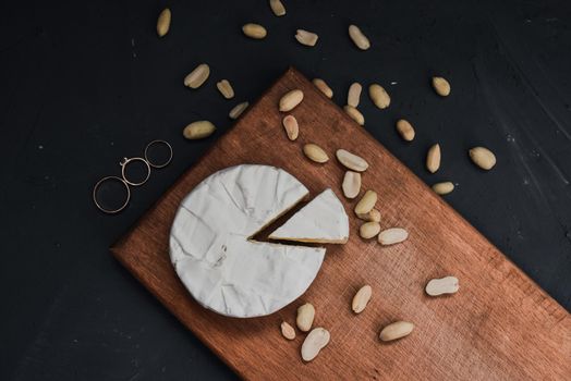 cheese camembert with mold and nuts and wedding rings on the wooden cutting board