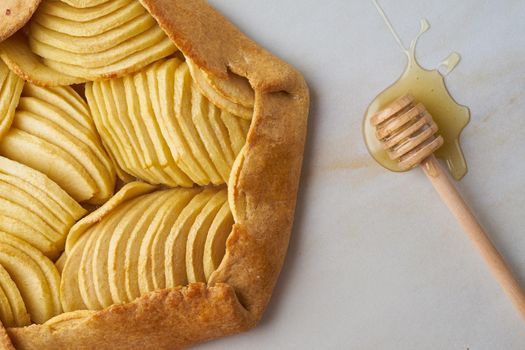 Apple galette, close up pie with fruits and honey, sweet pastries on marble table, top view