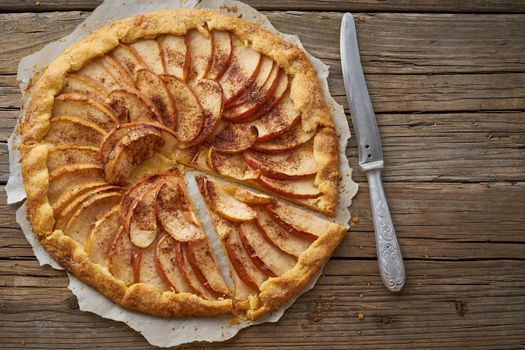 Apple pie, galette with fruits, sweet pastries on old wooden rustic table, copy space.