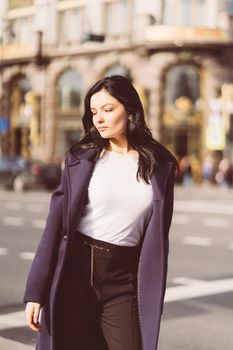 Portrait f beautiful intelligent brunette who walks down street of Saint-Petersburg in city center. Charming thoughtful woman with a long dark hair wanders alone, immersed in thoughts, copy space