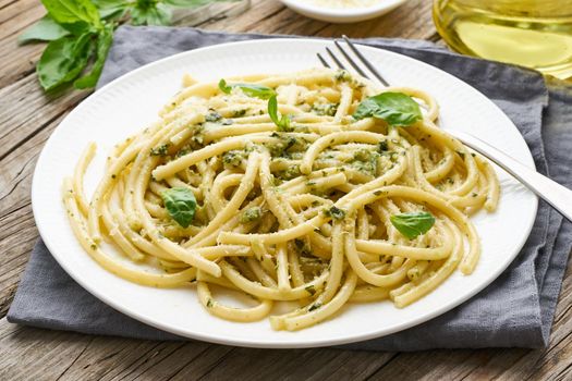 Pesto spaghetti pasta with basil, garlic, pine nuts, olive oil. Rustic table, side view, close up