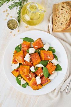 Salad with roasted pumpkin, feta cheese, spinach, nuts with honey and seasonings, top view
