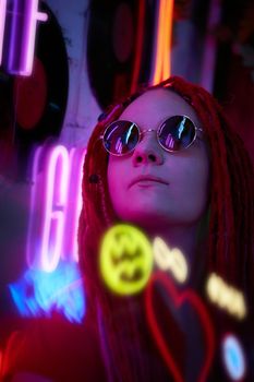 Girl in neon lights at party in nightclub, beautiful woman in sunglasses, with long pink hair, with dreadlocks pigtails, bright and stylish in the glow of neon signs, vertical