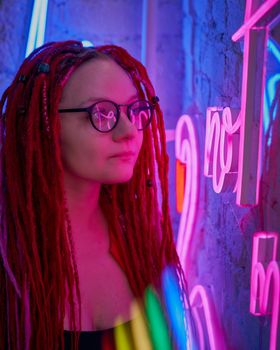 Girl in neon lights at party in nightclub, beautiful woman in sunglasses, with long pink hair, with dreadlocks pigtails, bright and stylish in the glow of neon signs