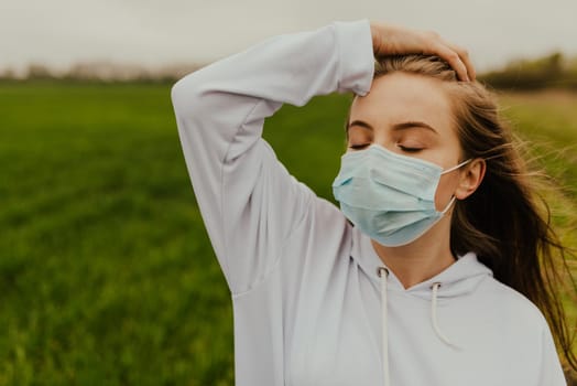 Young blond European woman in a protective mask outdoors.