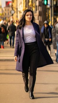 Beautiful serious smart brunette girl walking down street of St. Petersburg in city center. Charming thoughtful fashionable woman with long dark hair wanders alone