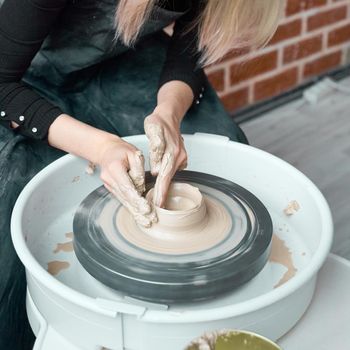 Woman making ceramic pottery on wheel, hands close-up, creation of ceramic ware. Handwork, craft, manual labor, buisness. Earn extra money, turning hobbies into cash and turning passion into a job