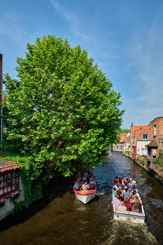 BRUGES, BELGIUM - MAY 28, 2018: Tourist boats with tourists in canal between old houses. Brugge Bruges, Belgium