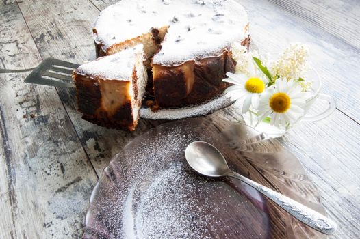 Cheesecake on an old table with a bouquet of daisies and a form for baking. Retro style. From the series "Still Life with cheesecake"