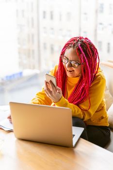 Woman looks at a mobile phone, gets angry, yells, annoyed at interlocutor. Girl with long pink hair yells at customer, client, boss. Difficulties in understanding, in work, in online communication