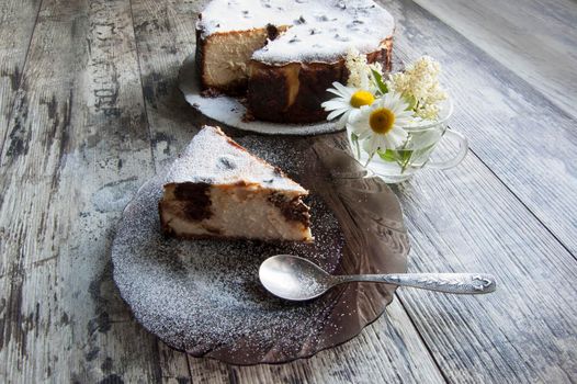 Slice of Cheesecake on an glass plate with a bouquet of daisies and a form for baking. Retro style. From the series "Still Life with cheesecake"