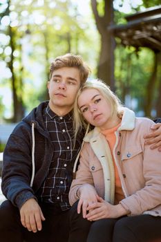 Girlfriend and Boyfriend falling in love, sitting and dreaming in Park near fountain in fall. Concept of love and happiness. Glare, flare. Vertical.