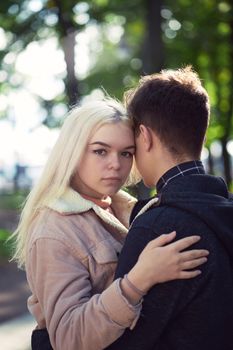 Girl put her head on his head, love in autumn park, teen couple. Concept of relationship teenagers, vertical