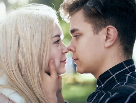 A man affectionately call looks at woman, guy and girl are worth close, touching the tips noses. Concept of teenage love and first kiss, close up