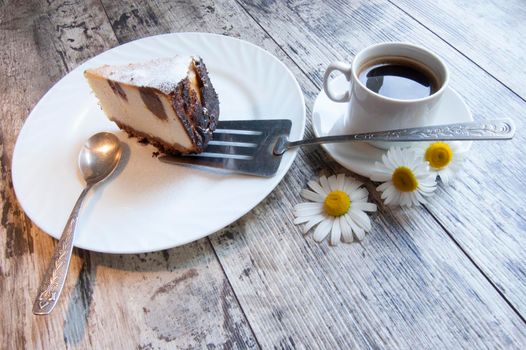 Slice of cheesecake on an old table with a tree camomile and cap of cofee. Retro style. From the series "Still Life with cheesecake"