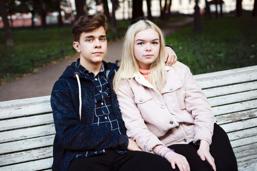 teenagers in love sit on a Park bench in autumn and looking straight ahead