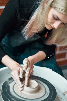 Beautiful woman making ceramic pottery on wheel, closeup. Concept for female in freelance, business, hobby. Earn extra money, money making, turning hobbies into cash and passion into job, vertical