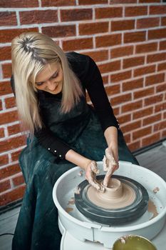 Woman making ceramic pottery on wheel. Concept for woman in freelance, business. Handcraft product. Earn extra money, side hustle, turning hobbies into cash and passion into a job