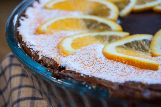 Chocolate cheesecake in a baking dish decorated with beaten egg whites and orange slices