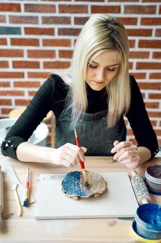 Woman making pattern on ceramic plate with paint brush. Creative hobby concept. Earn extra money, side hustle, turning hobbies into cash, passion into a job, vertical