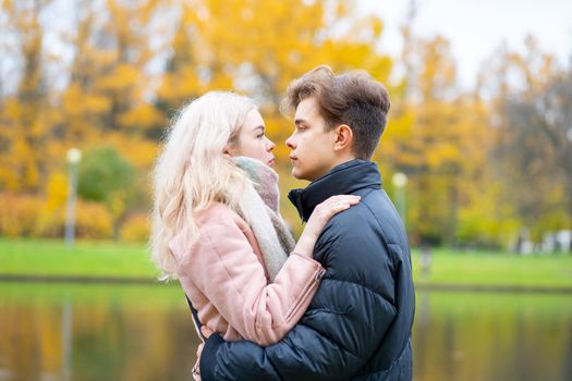 Lovely brunette guy and pretty girl blonde drink coffee and talking on a date. Loving teenagers are happy, smiling, kissing. Teen Love Concept. Outdoor.