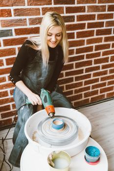 Woman making ceramic pottery on wheel, blow dry clay blanks. Concept for woman in freelance, business. Handcraft product. Earn extra money, side hustle, turning hobbies into cash, passion into job
