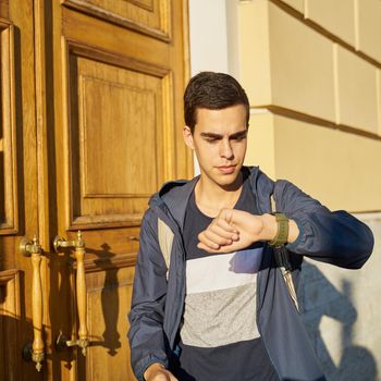 Young adult looks at watch. Stressed caucasian man with black hair afraid of getting late. Girl is late for a date