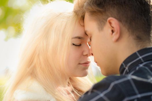 A man affectionately call looks at woman, guy and girl are worth close, touching the tips noses. The concept of first teenage love and first kiss. Boy and girl, couple. Intimacy, honesty, trust, open feelings. Close up portrait.