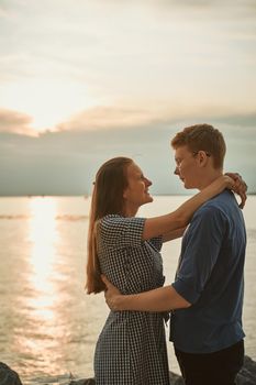 teen couple on beach at the sunset, girl look at boy and smile