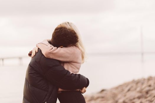 Lovely brunette guy and pretty girl blonde embracing. Loving teenagers are happy, smiling, kissing. Teen Love Concept. Outdoor, close up