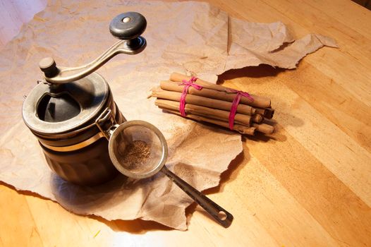 Cinnamon sticks on a wooden table. Near a coffee grinder and packaging papers.