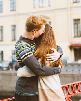 red-haired man kisses a woman on the top of her head, a boy in a sweater soothes and comforts a girl with long dark thick hair