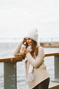 Beautiful young girl drinking coffee, tea from a plastic mug. Winter, Christmas eve, new year's eve. Woman with long hair prepares to travel, Scandinavian style