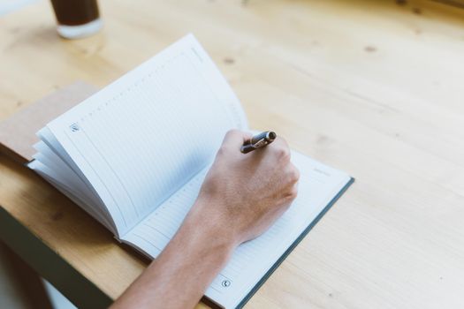 Young man, unrecognizable person writing information to notepad, teenager in casual clothes plans schedule, daily, to-do list