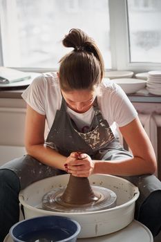 Beautiful woman making ceramic pottery on wheel, hands close-up. Concept for woman in freelance, business, hobby