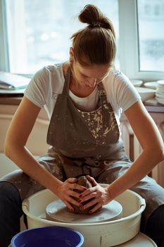 Beautiful woman making ceramic pottery on wheel, hands close-up. Concept for woman in freelance, business, hobby