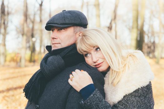 Closeup portrait of a happy blonde mature woman and beautiful middle-aged brunette, looking away. Pensive, dreamy loving couple of 45-50 years old walks in the autumn park in warm clothes, in a coat and enjoys life