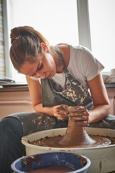 Beautiful woman making ceramic pottery on wheel, hands close-up. Concept for woman in freelance, business, hobby