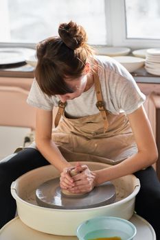 Beautiful woman making ceramic pottery on wheel, hands close-up. Concept for woman in freelance, business, hobby